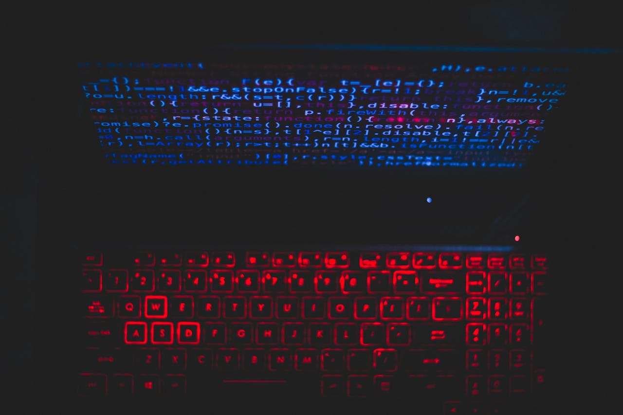 Services-02 Dark-themed laptop setup with a red glowing keyboard and code on screen, ideal for tech enthusiasts.